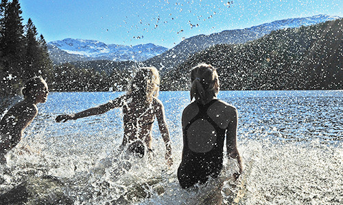 Tre barn som vasser og spruter med vann overalt